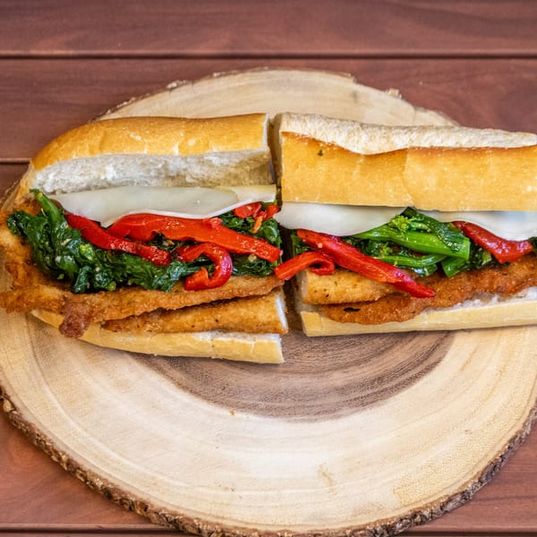 A P&M Fine Foods deli sandwich with fried cutlets, broccoli rabe, roasted red peppers, and cheese.