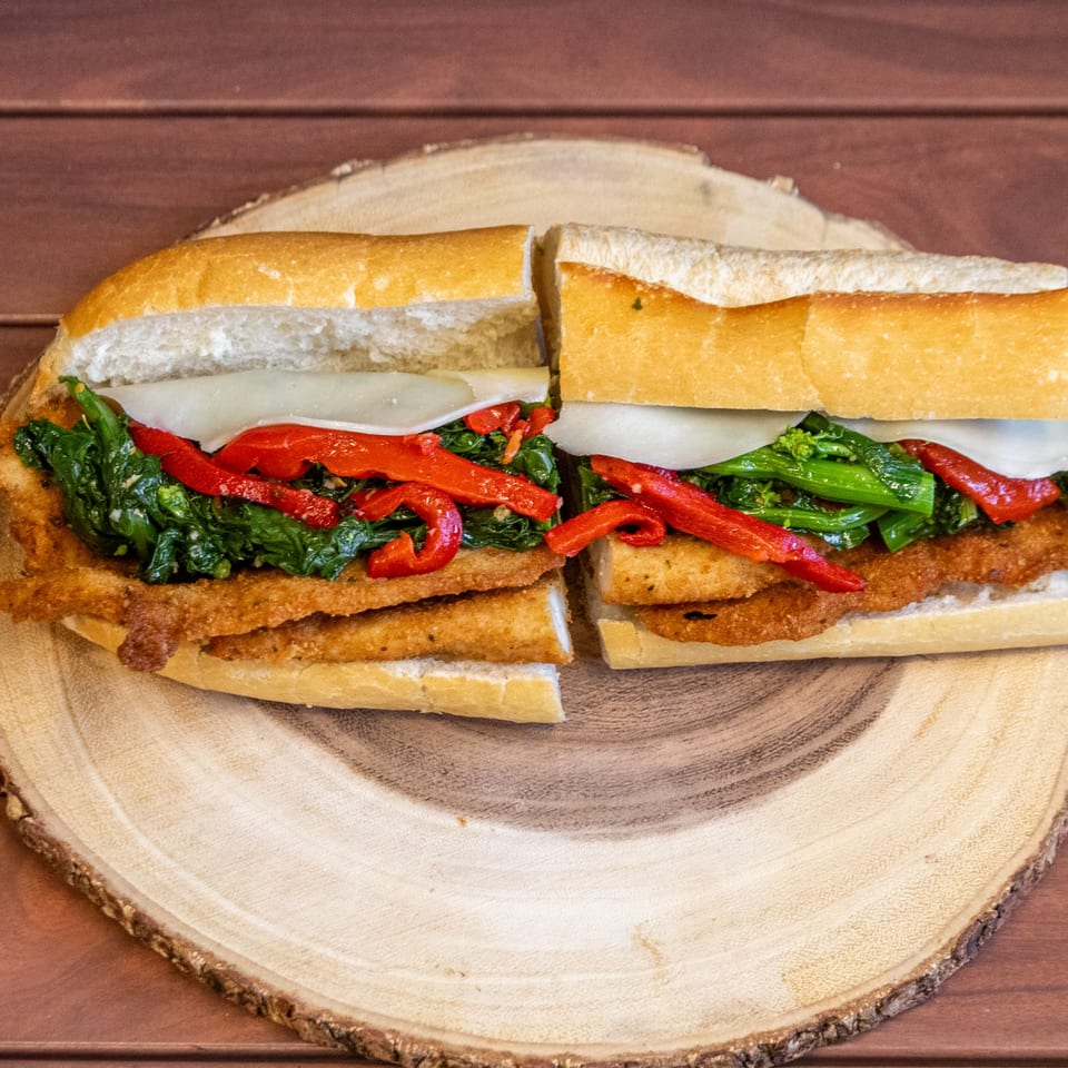 A P&M Fine Foods deli sandwich with fried cutlets, broccoli rabe, roasted red peppers, and cheese.