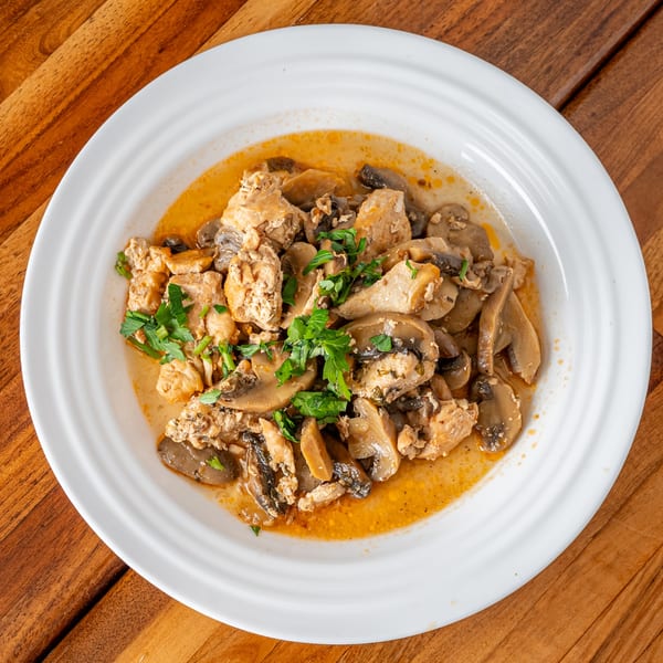 P&M Fine Foods' chicken and mushrooms in a creamy sauce, garnished with fresh parsley.
